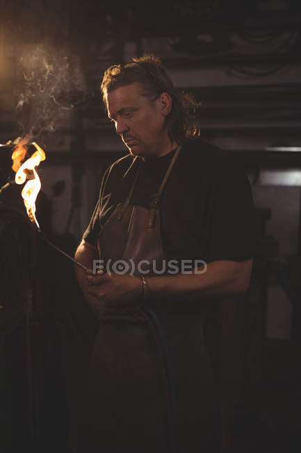 Blacksmith holding welding pipe in workshop — Stock Photo