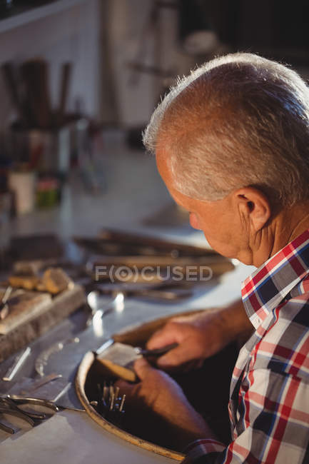 Attentive goldsmith shaping metal with pliers in workshop — Stock Photo