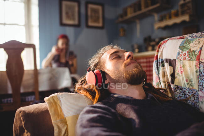 Hipster-Mann hört Musik, während er es sich zu Hause auf Sofa gemütlich macht — Stockfoto