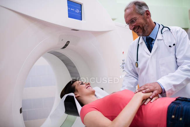 Médico sonriente consolando al paciente antes de la resonancia magnética en el hospital - foto de stock