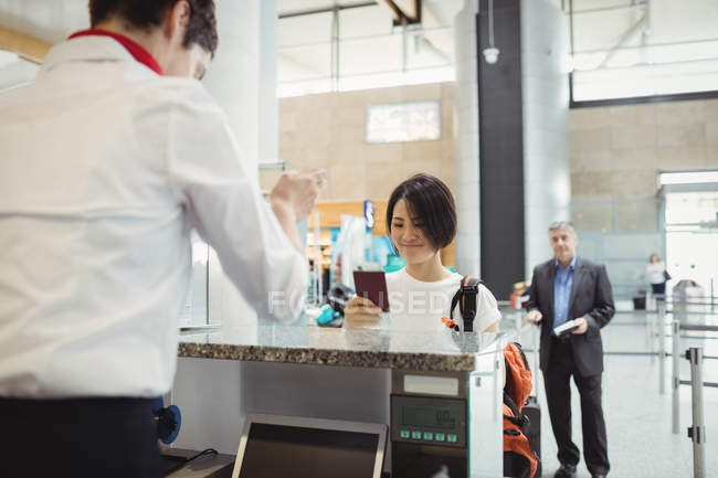 Flugbegleiter reicht Passagieren am Flughafen-Check-in-Schalter den Reisepass — Stockfoto