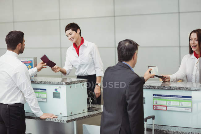 Préposés à l'enregistrement des compagnies aériennes remettant un passeport aux passagers au comptoir d'enregistrement de l'aéroport — Photo de stock