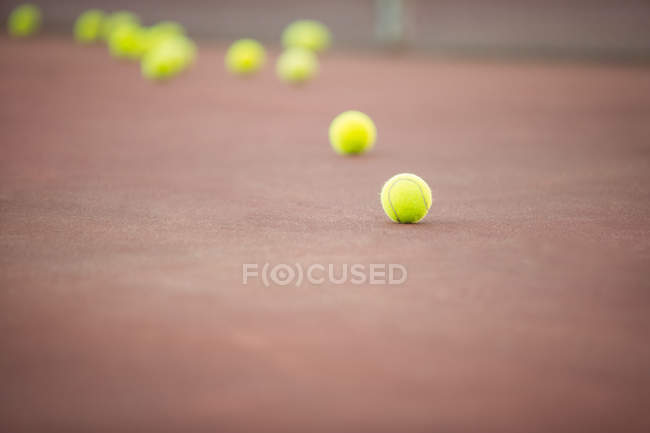 Bolas de tênis deitado na quadra de esporte marrom — Fotografia de Stock