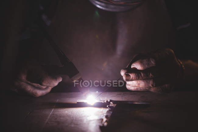 Forgeron soudant un métal en atelier — Photo de stock
