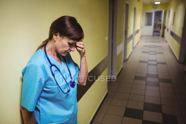 Enfermeira deprimida em pé no corredor hospitalar — Fotografia de Stock