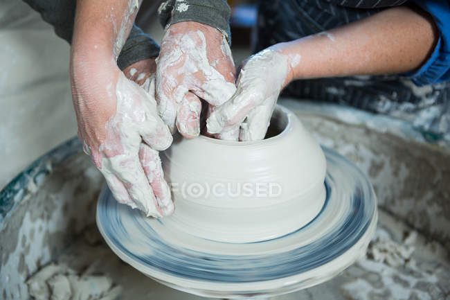 Close-up de oleiro masculino ajudando oleiro feminino na oficina de cerâmica — Fotografia de Stock