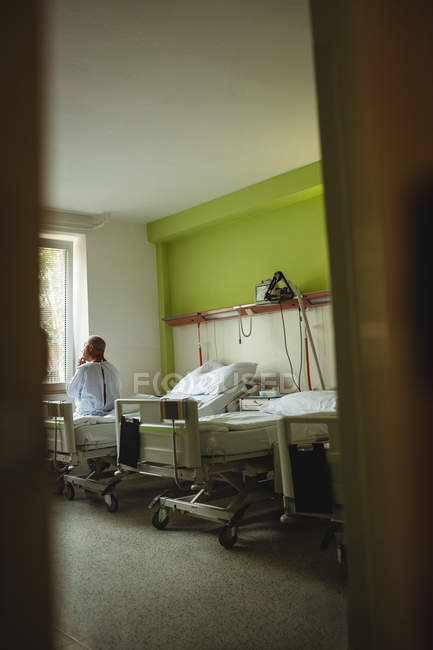 Hombre mayor sentado en una cama en el hospital - foto de stock