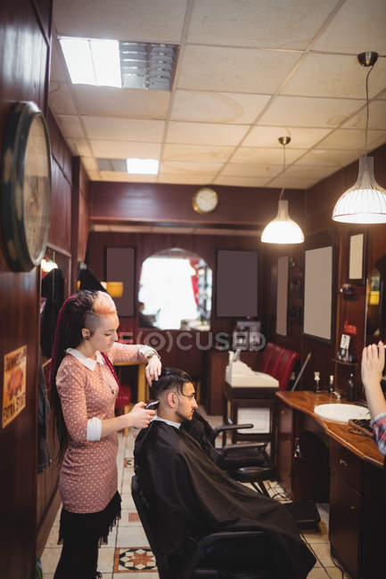 Hombre consiguiendo su pelo recortado con trimmer en peluquería - foto de stock