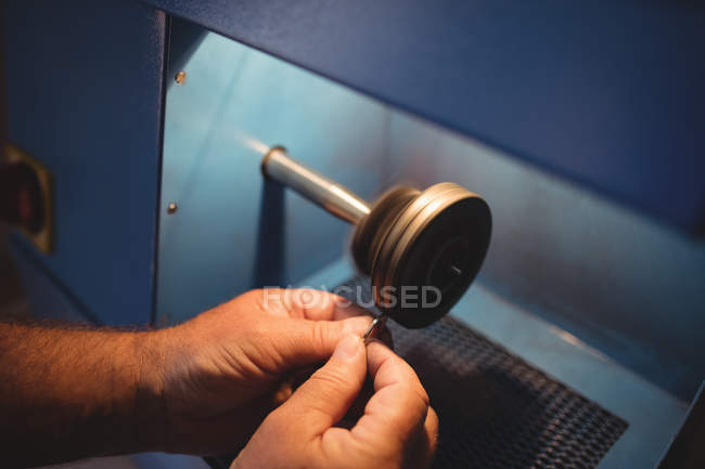Cropped image of goldsmith polishing ring in workshop — Stock Photo