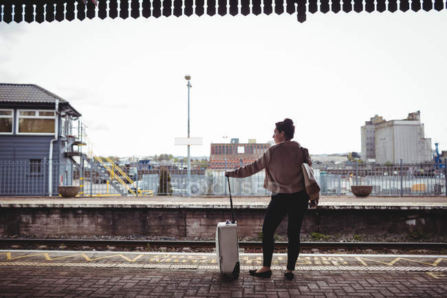 Longitud total de la mujer de pie en la plataforma de la estación de ferrocarril - foto de stock