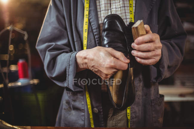 Gros plan d'un cordonnier polissant une chaussure en atelier — Photo de stock