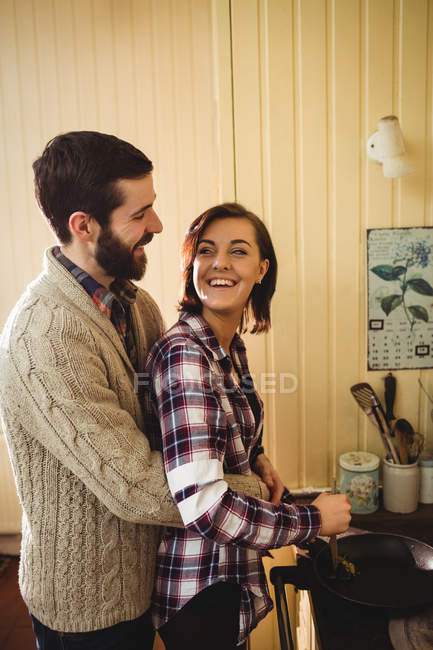 Embracing couple preparing food together in kitchen at home — Stock Photo