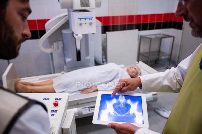 Médecins examinant les rayons X sur tablette numérique à l'hôpital — Photo de stock