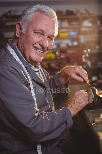 Старший сапожник чинит обувь в мастерской — стоковое фото