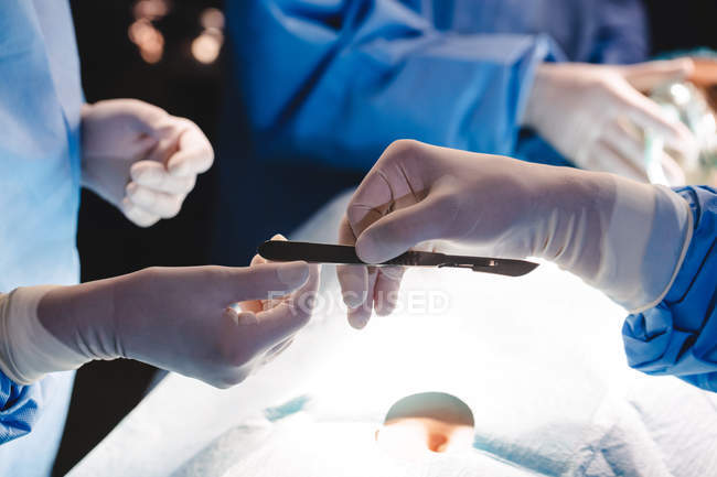 Хірурги віддають операційне лезо колезі в операційній кімнаті в лікарні — стокове фото