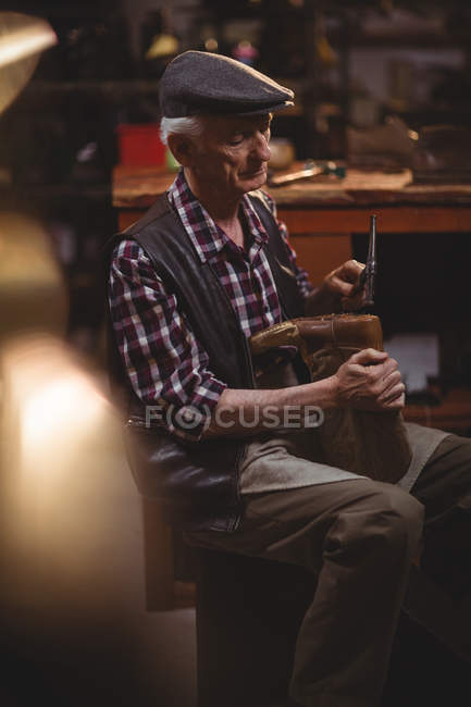 Sapateiro martelando em um sapato na oficina — Fotografia de Stock