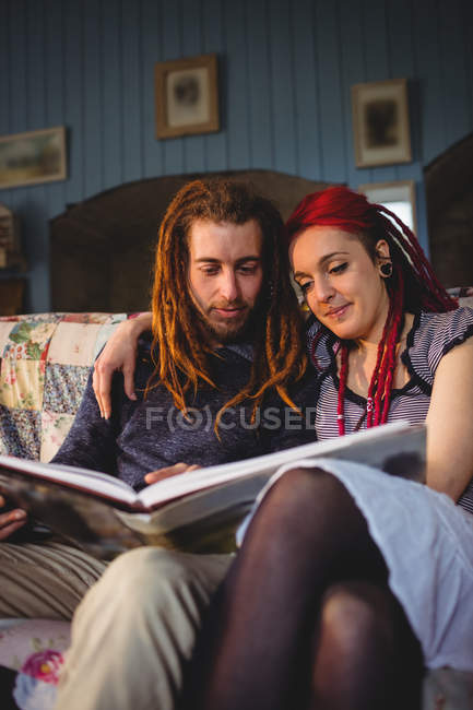 Hipster coppia in cerca di album fotografico mentre seduto a casa — Foto stock