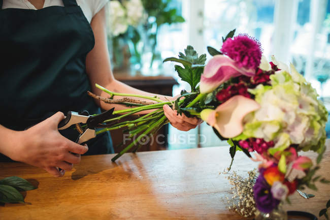 Abgeschnittenes Bild einer Floristin, die in ihrem Blumenladen Blütenstiele schneidet — Stockfoto