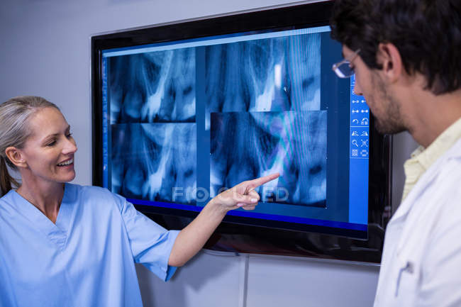 Assistente odontológico e dentista discutindo raio-X no monitor na clínica odontológica — Fotografia de Stock