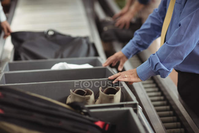 Mann steckt Schuhe für Sicherheitskontrolle am Flughafen in Tablett — Stockfoto