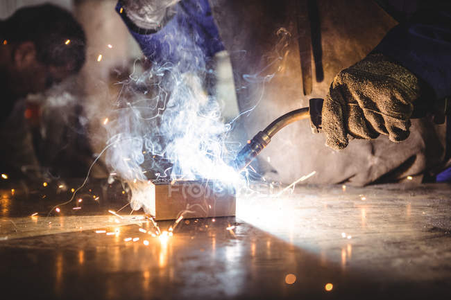 Cropped image of welder welding metal in workshop — Stock Photo