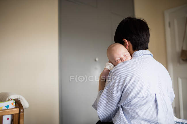 Rear view of mother holding her sleeping baby at home — Stock Photo