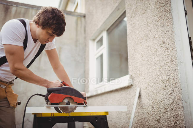 Carpenter cutting wooden frame from circular saw outside house — Stock Photo
