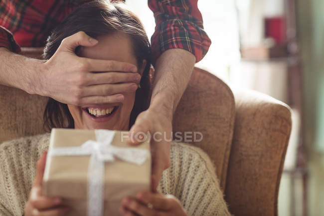Homem mulher surpreendente com um presente na sala de estar em casa — Fotografia de Stock