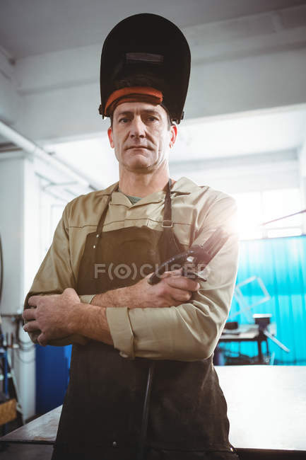 Retrato de soldador de pie con los brazos cruzados en taller - foto de stock