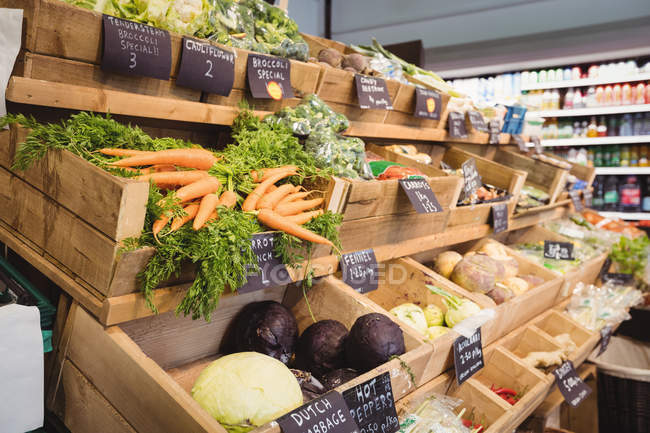 Variedad de verduras en cajas de madera en el supermercado - foto de stock