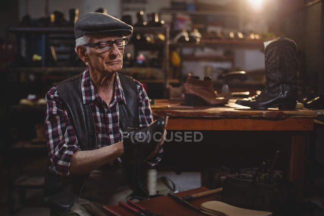 Calzolaio anziano che ripara una scarpa in officina — Foto stock
