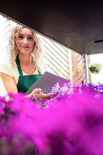 Жіночий флорист перевіряє квіти в садовому центрі — стокове фото