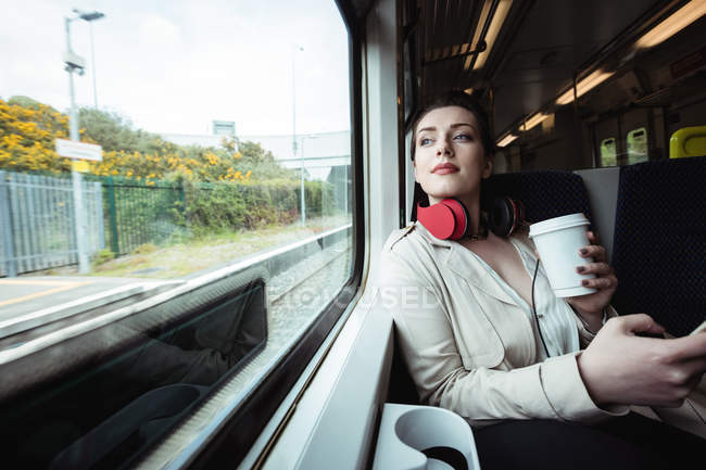 Beautiful woman sitting by window in train — Stock Photo