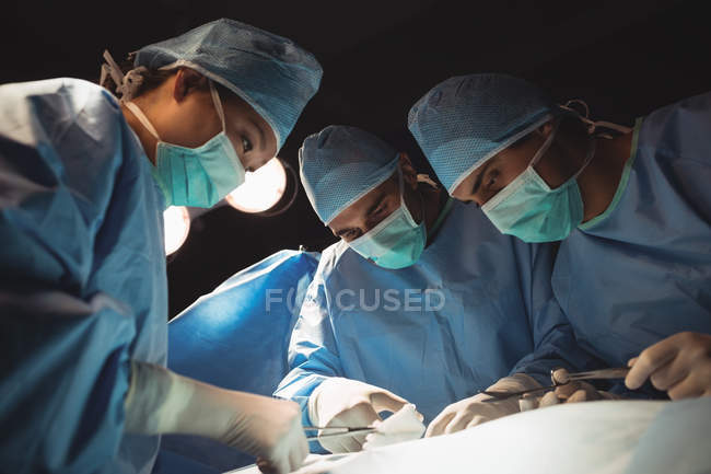 Équipe de chirurgiens effectuant une opération en salle d'opération à l'hôpital — Photo de stock
