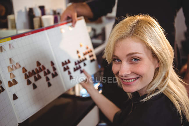 Femme sélectionnant la couleur des cheveux avec styliste au salon de coiffure — Photo de stock