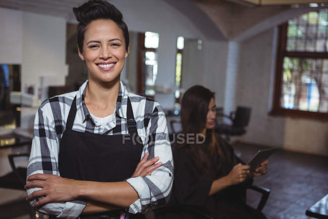 Portrait of female hairdresser standing with arms crossed at salon — Stock Photo