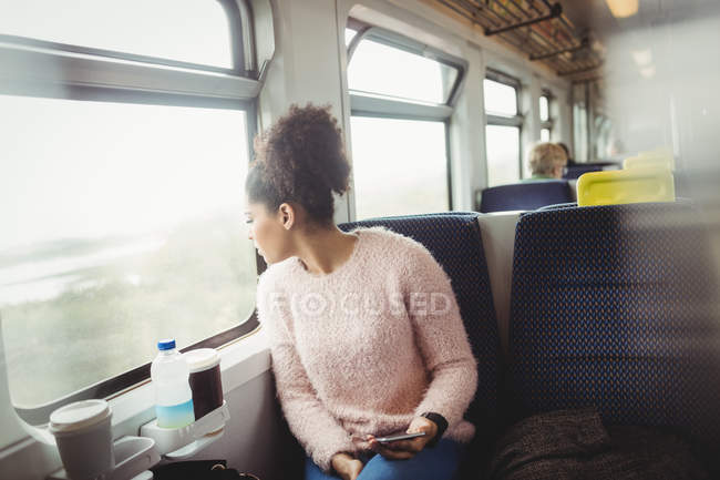 Frau schaut durch Fenster, während sie im Zug sitzt — Stockfoto