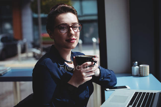 Портрет молодой женщины, держащей чашку кофе в кафе — стоковое фото