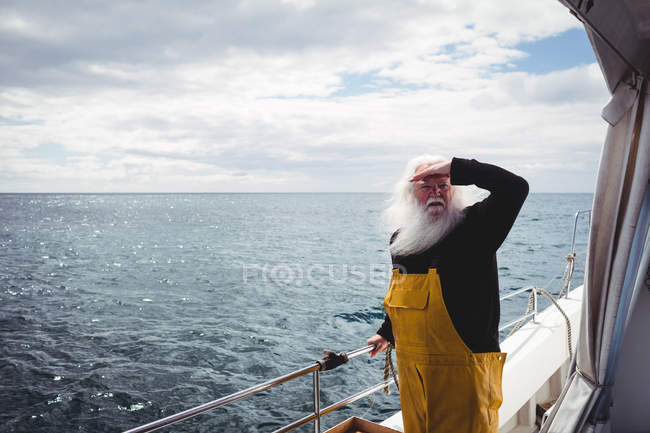 Pêcheur debout sur le bateau et regardant loin — Photo de stock