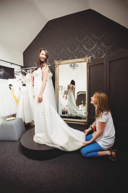 Femme essayant sur robe de mariée en studio avec l'aide de concepteur créatif — Photo de stock