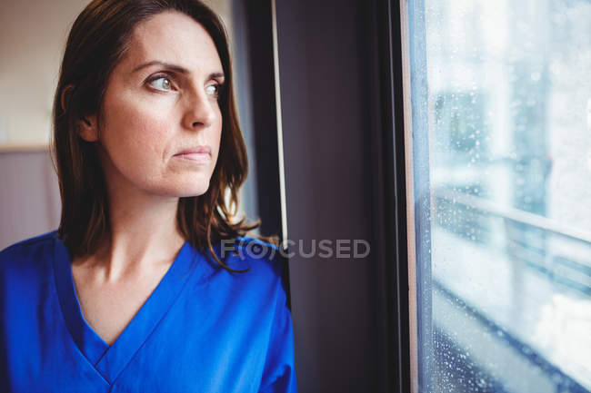 Медсестра смотрит в окно в больнице — стоковое фото