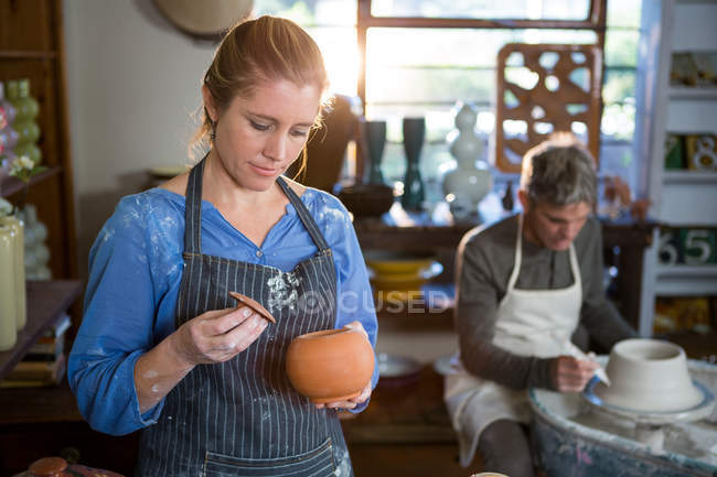 Female potter checking pot in pottery workshop — Stock Photo