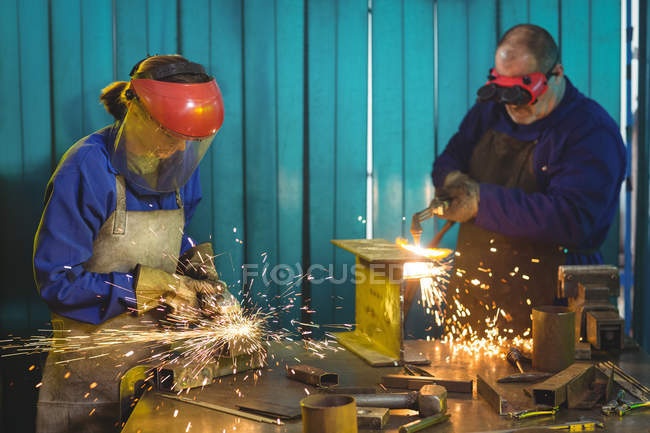 Soudeurs masculins et féminins travaillant ensemble en atelier — Photo de stock