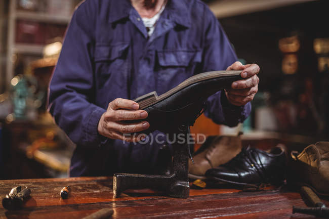 Section médiane du cordonnier masculin réparant une chaussure en atelier — Photo de stock