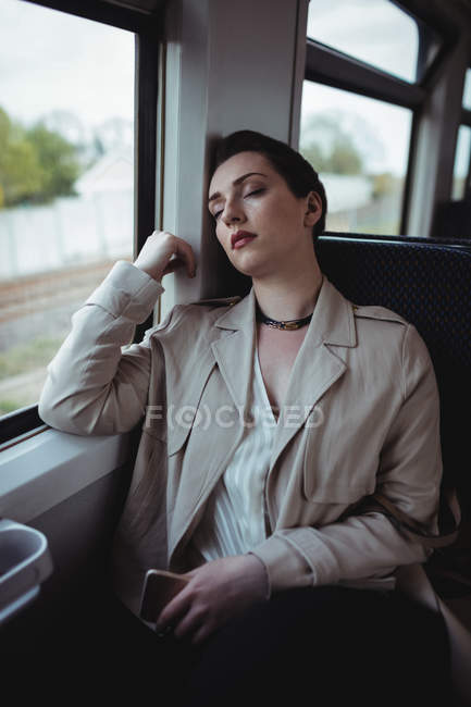 Young woman sleeping by window in train — Stock Photo