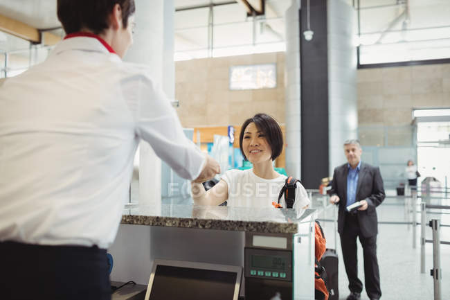 Le préposé à l'enregistrement des compagnies aériennes remet son passeport au passager au comptoir d'enregistrement de l'aéroport — Photo de stock