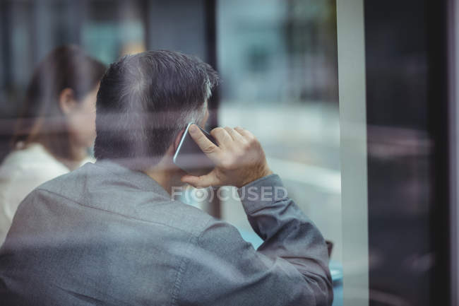 Человек разговаривает по мобильному телефону в кафетерии — стоковое фото