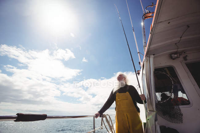 Low angle view of Fisherman holding fishing rod and looking at view from boat — Stock Photo