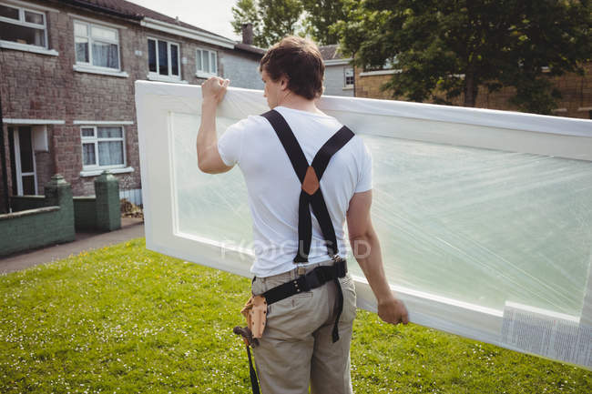 Back view of Carpenter carrying door on lawn — Stock Photo