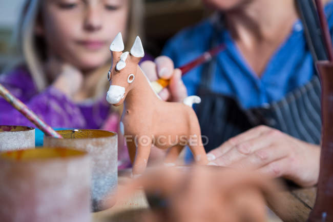 Close-up de oleiro feminino ajudando menina na pintura na oficina de cerâmica — Fotografia de Stock